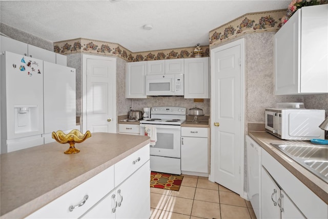 kitchen featuring white cabinetry, white appliances, a textured ceiling, sink, and light tile patterned flooring