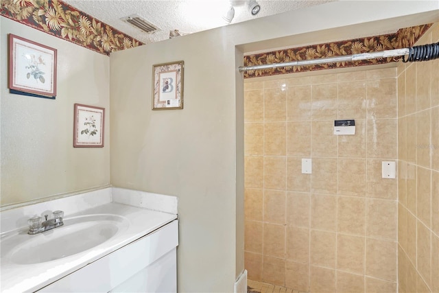 bathroom featuring vanity, a textured ceiling, and tiled shower