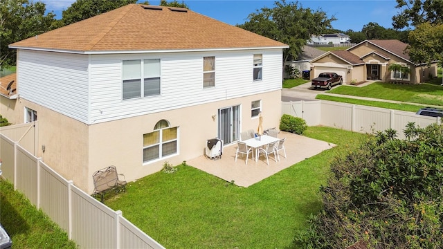 back of property featuring a yard, a garage, and a patio