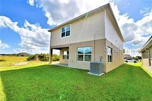 back of property featuring a yard and central air condition unit