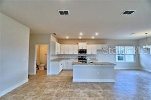 kitchen with appliances with stainless steel finishes, white cabinetry, and a center island with sink