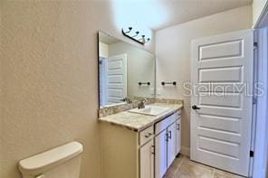 bathroom featuring vanity, toilet, and tile patterned flooring