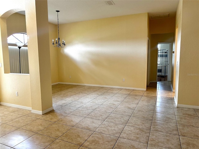 tiled spare room with a chandelier