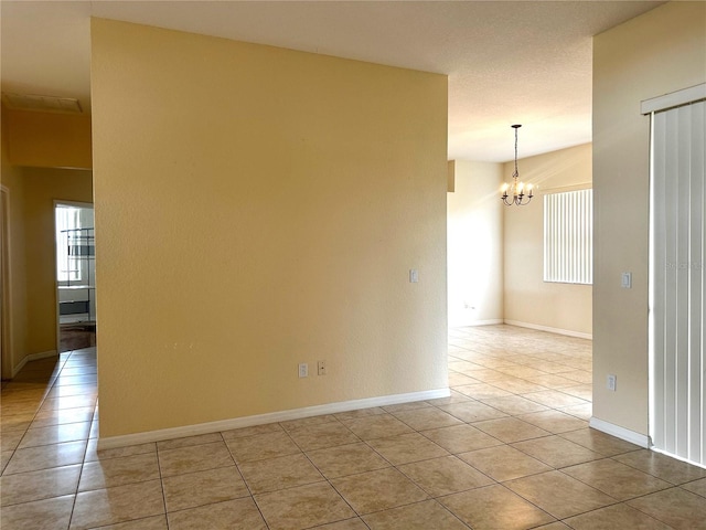 unfurnished room featuring a textured ceiling, a chandelier, and light tile patterned floors