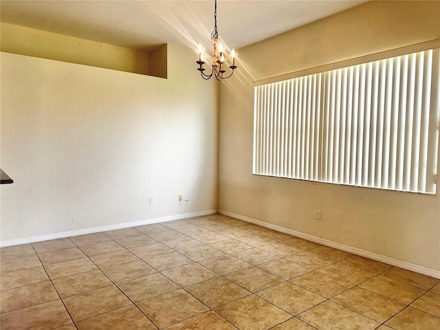 tiled spare room featuring an inviting chandelier