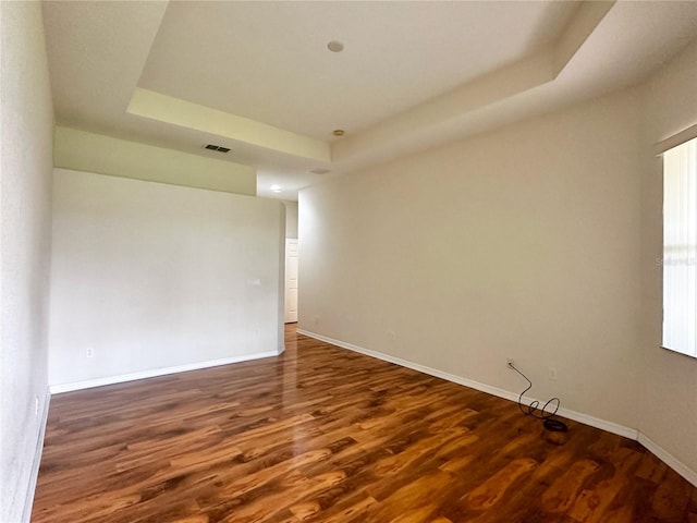 empty room featuring a tray ceiling and dark wood-type flooring