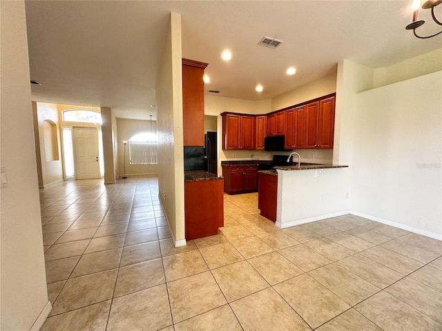 kitchen with sink, black appliances, kitchen peninsula, light tile patterned flooring, and a breakfast bar