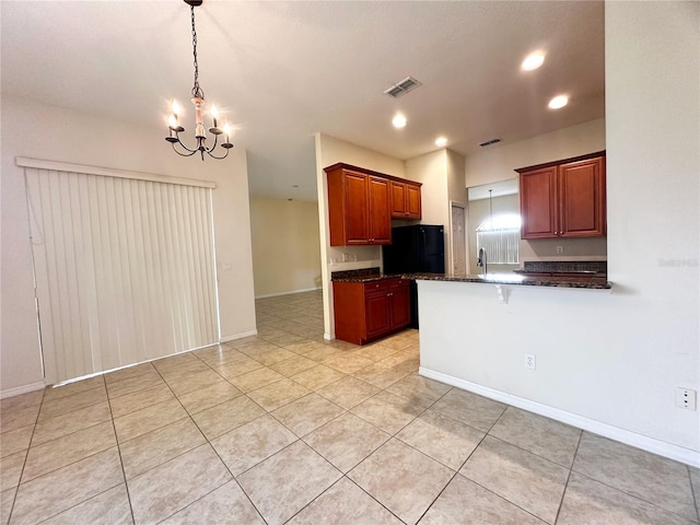 kitchen with black refrigerator, decorative light fixtures, kitchen peninsula, an inviting chandelier, and sink