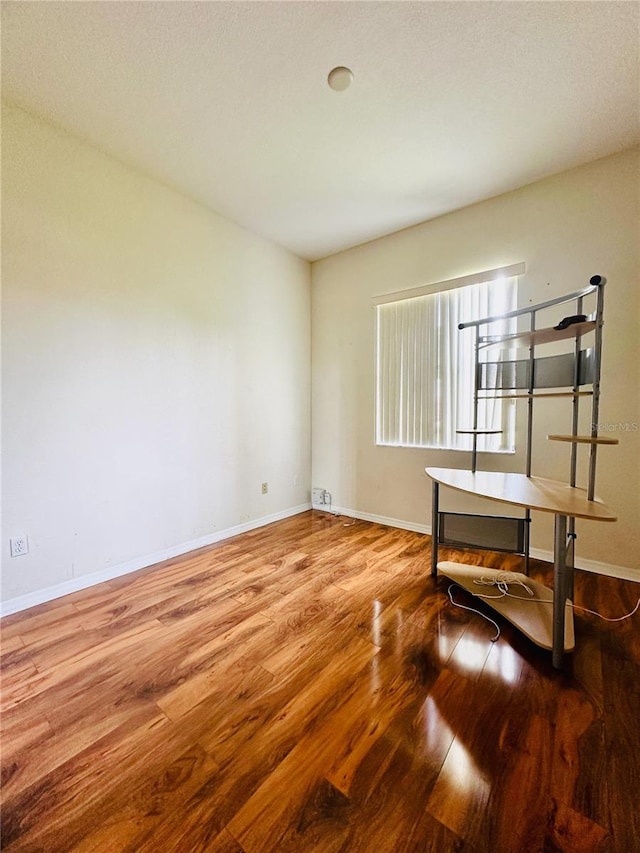 unfurnished room with a textured ceiling and wood-type flooring