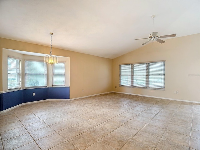 tiled spare room with ceiling fan with notable chandelier, a wealth of natural light, and vaulted ceiling