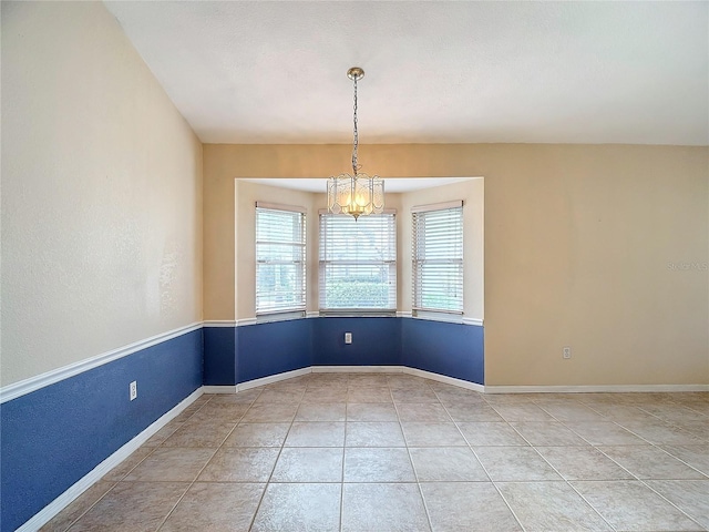 spare room with an inviting chandelier and tile patterned floors