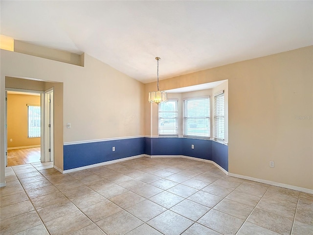 tiled empty room featuring vaulted ceiling and a notable chandelier