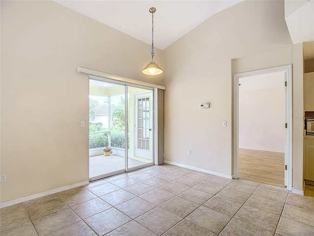 empty room with vaulted ceiling and light tile patterned floors