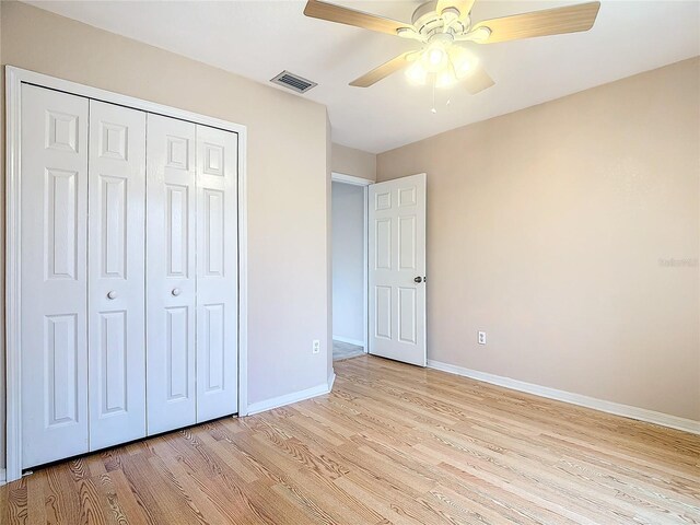 unfurnished bedroom with light wood-type flooring, ceiling fan, and a closet