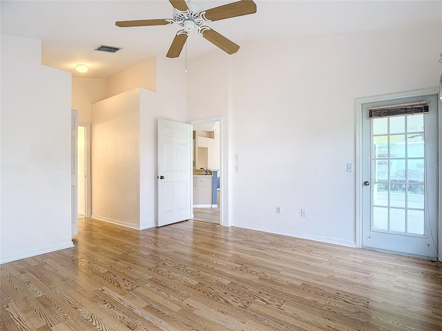 empty room with ceiling fan, light hardwood / wood-style flooring, and vaulted ceiling