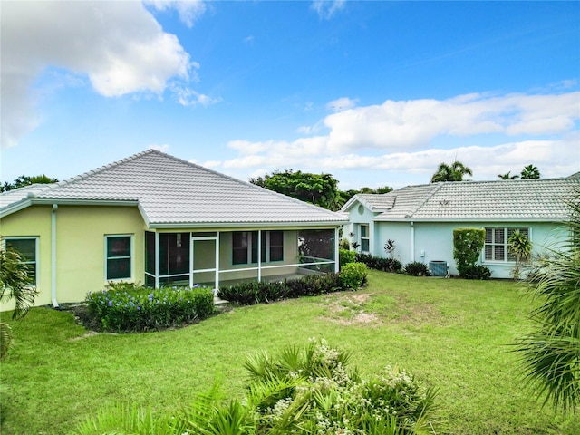 rear view of property featuring a lawn, a sunroom, and central AC unit