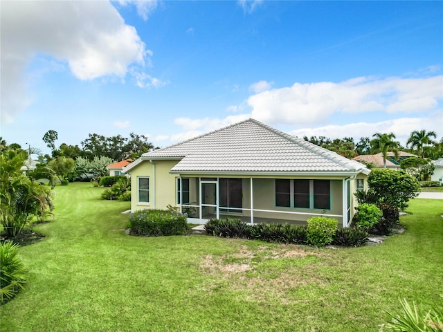 rear view of property featuring a yard and a sunroom