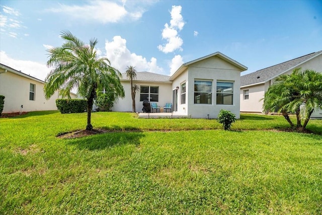 rear view of property with a lawn and stucco siding