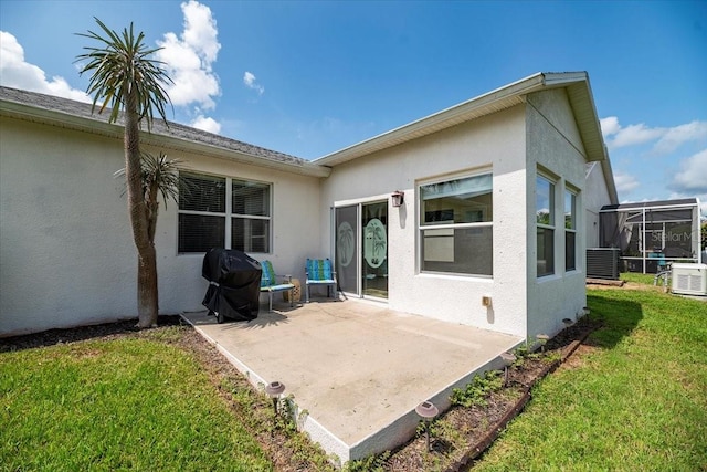 back of house with a patio, glass enclosure, a yard, central AC, and stucco siding