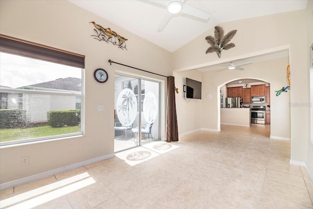 empty room with a ceiling fan, arched walkways, and plenty of natural light