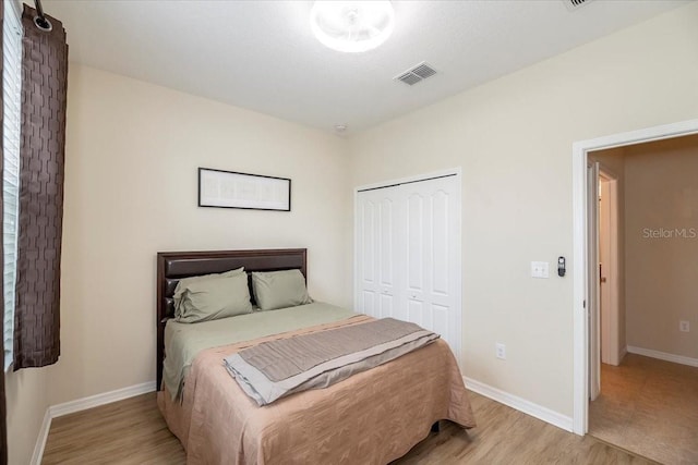 bedroom featuring light wood-type flooring, baseboards, visible vents, and a closet