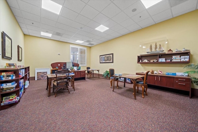 interior space with a paneled ceiling and dark colored carpet