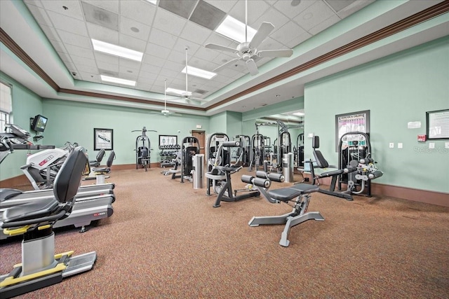 gym featuring a ceiling fan, a tray ceiling, a drop ceiling, and baseboards