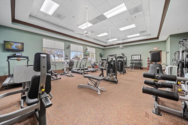 exercise room with a paneled ceiling, ceiling fan, and a tray ceiling