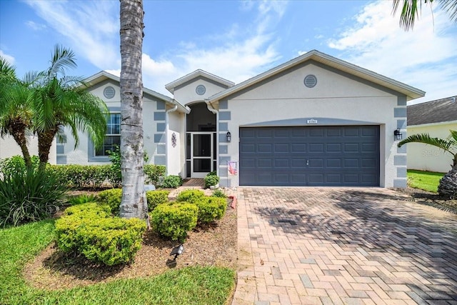 ranch-style home with a garage, decorative driveway, and stucco siding