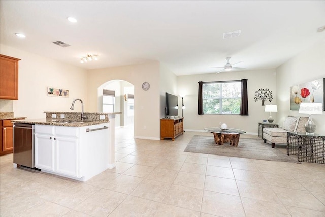 kitchen featuring arched walkways, brown cabinets, visible vents, open floor plan, and a sink