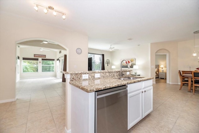 kitchen featuring arched walkways, dishwasher, open floor plan, white cabinetry, and a sink