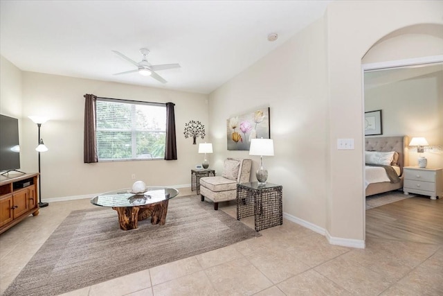 living area featuring light tile patterned floors, ceiling fan, and baseboards