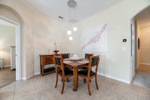 dining area featuring arched walkways, visible vents, and baseboards