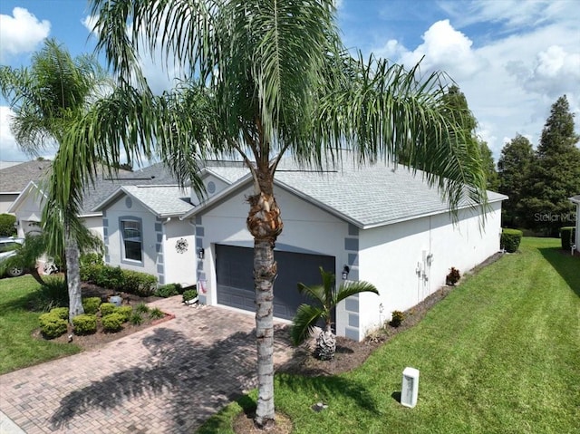 view of front of home with an attached garage, roof with shingles, decorative driveway, stucco siding, and a front lawn