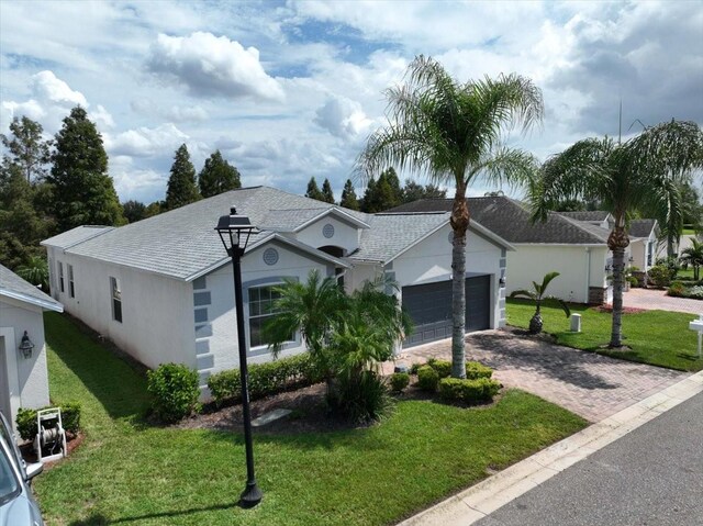 ranch-style house with a garage, stucco siding, decorative driveway, and a front yard