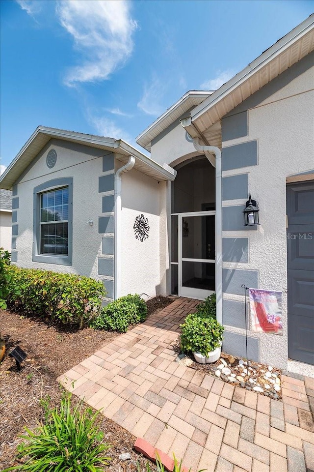 doorway to property with an attached garage and stucco siding