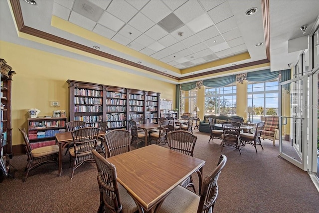 dining room featuring dark carpet, a raised ceiling, and ornamental molding