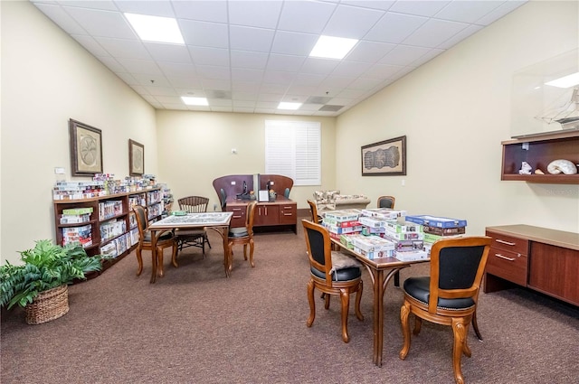 carpeted dining area featuring a paneled ceiling