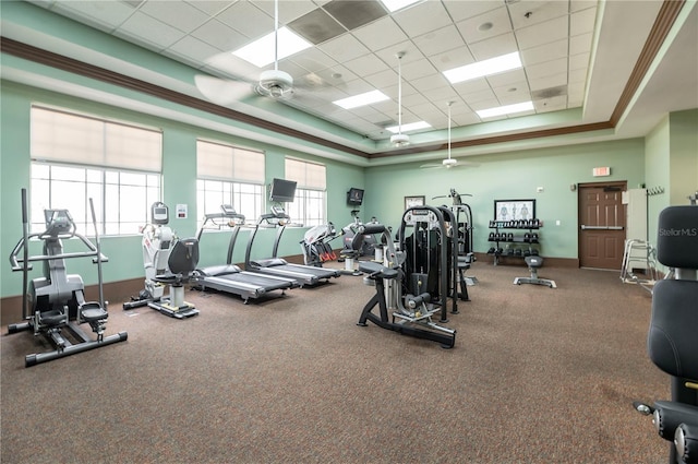 exercise room with a paneled ceiling, a raised ceiling, and a ceiling fan