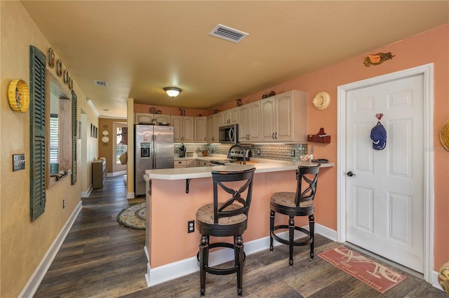 kitchen with a kitchen breakfast bar, dark wood-type flooring, kitchen peninsula, and stainless steel appliances