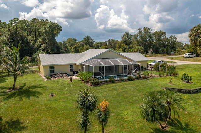 rear view of property featuring glass enclosure and a lawn