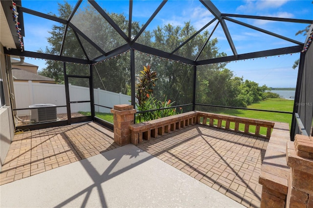 view of patio / terrace featuring central AC unit, a lanai, and a water view