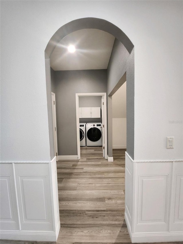 clothes washing area featuring cabinets, light hardwood / wood-style flooring, and independent washer and dryer