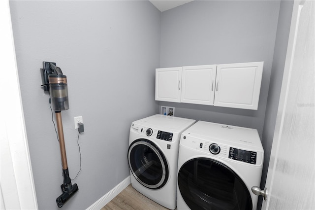 laundry room with light hardwood / wood-style flooring, cabinets, and washing machine and clothes dryer