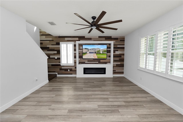 unfurnished living room with ceiling fan and wood walls