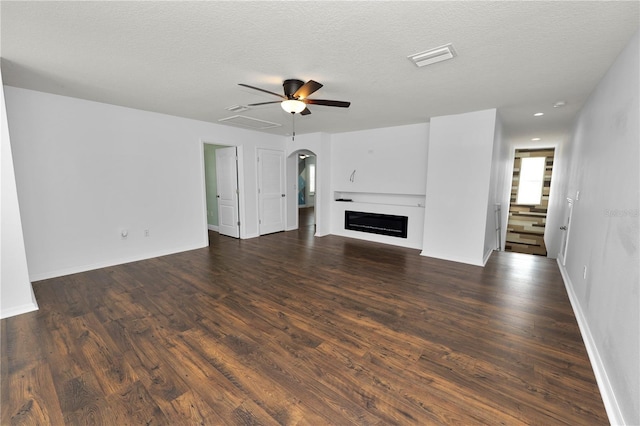 unfurnished living room with dark hardwood / wood-style flooring, ceiling fan, and a textured ceiling