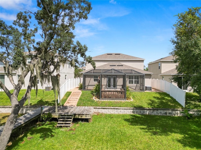 rear view of property featuring a yard, glass enclosure, and central air condition unit