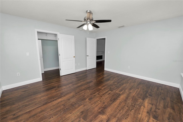 unfurnished bedroom featuring a textured ceiling, dark wood-type flooring, a closet, and ceiling fan