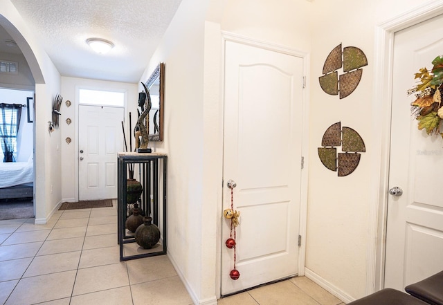 hall featuring light tile patterned floors and a textured ceiling