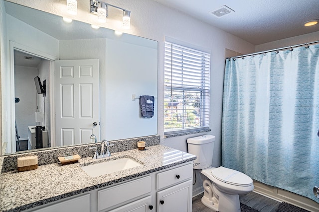 bathroom featuring a shower with curtain, a textured ceiling, vanity, and toilet